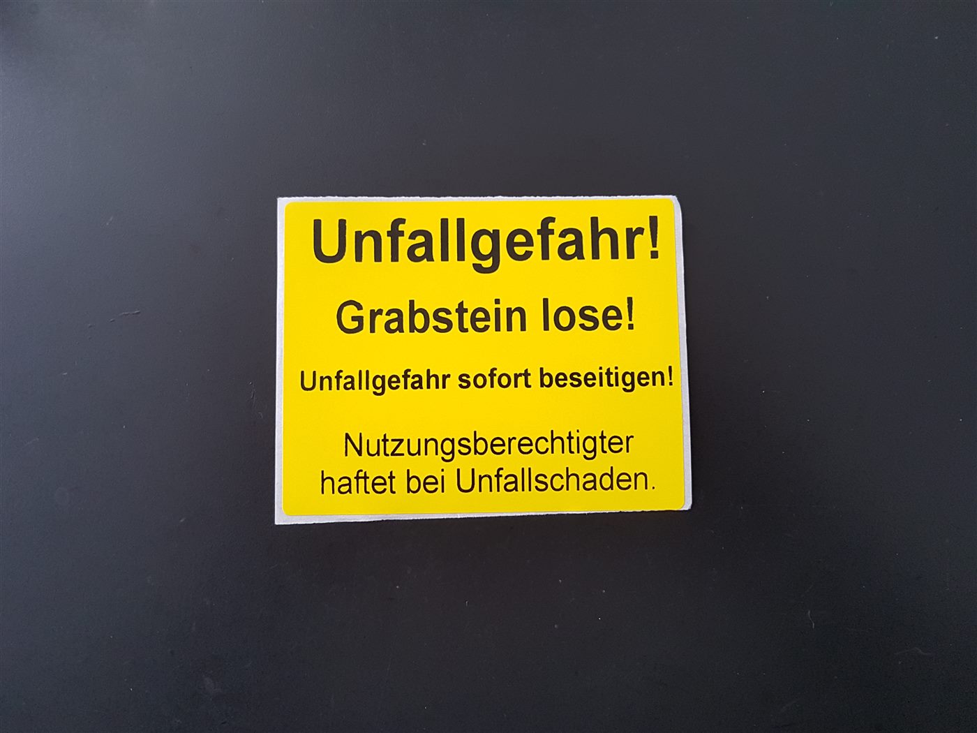 Gelber Warnaufkleber bei nicht standsicheren Grabmalen